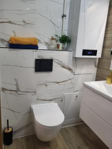 a white bathroom with a toilet and a sink at Apartament Perełka in Jelenia Góra