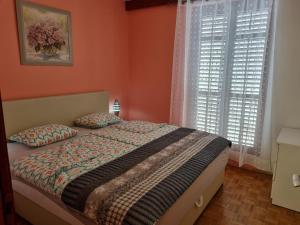 a bedroom with orange walls and a bed with two pillows at Apartments Jelena in Peroj