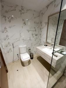 a bathroom with a toilet and a sink and a mirror at BANIYAS PLAZA HOTEL APARTMENTS in Abu Dhabi