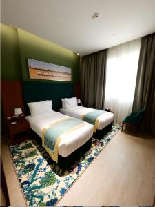 two beds in a hotel room with green walls at BANIYAS PLAZA HOTEL APARTMENTS in Abu Dhabi