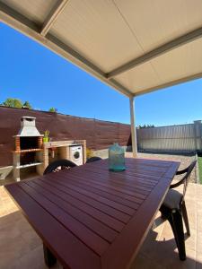 einen Holztisch auf einer Terrasse mit Grill in der Unterkunft Casita la Loma in Cádiz