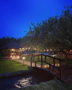 a wooden bridge over a pond at night at Horace Guesthouse POOL & HOT TUB & BIKES & RIVER in Dejani
