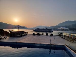 a swimming pool with a cruise ship in the water at Agape Rose Hotel in Tivat