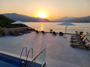 a pool with chairs and umbrellas with the sunset at Agape Rose Hotel in Tivat