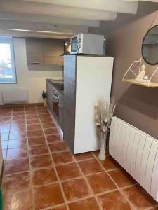 a kitchen with a brown tiled floor with a refrigerator at Gîte jusqu’à 4 personnes in Arches
