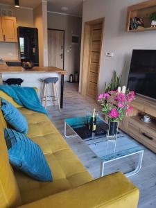 a living room with a yellow couch and a glass table at Apartament Perełka in Jelenia Góra