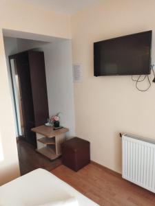 a bedroom with a tv on the wall and a table at Pensiunea Krystinne in Hunedoara