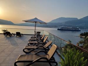 a row of chairs and an umbrella on a balcony with a cruise ship at Agape Rose Hotel in Tivat