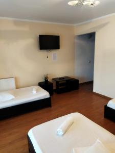 Habitación de hotel con 2 camas y TV de pantalla plana. en Pensiunea Krystinne, en Hunedoara