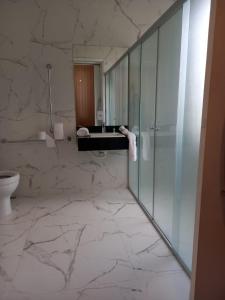 La salle de bains est pourvue d'une douche en verre et de toilettes. dans l'établissement Pousada Macanaíba, 