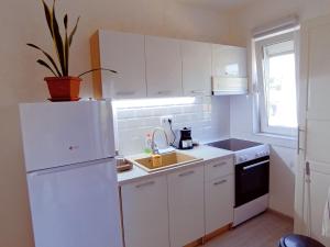 La cuisine blanche est équipée d'un évier et d'un réfrigérateur. dans l'établissement BIS Apartments, à Belgrade