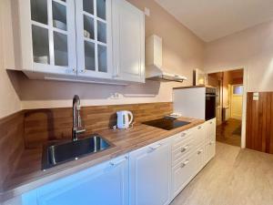 uma cozinha com armários brancos e um lavatório em Apartman Cinthia em Crikvenica