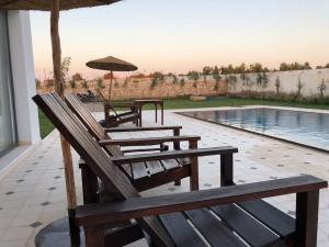 eine Gruppe Stühle und ein Sonnenschirm neben einem Pool in der Unterkunft Mood Villa Essaouira in Essaouira
