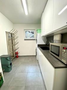 a kitchen with white cabinets and a microwave at Villa Number 8 in Feldberg