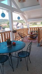 un patio con una mesa azul y sillas en un porche en Gîte des Roches, en La Chaux-du-Dombief