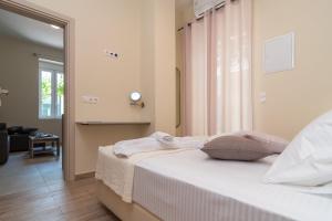 a bedroom with a bed with white sheets and a window at Gemma Apartments in Palaiochora