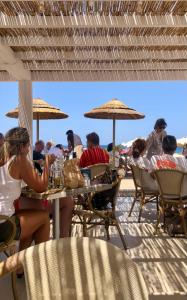 un groupe de personnes assises à des tables sur la plage dans l'établissement Appartamenti vicini al mare a Giglio campese, à Campese