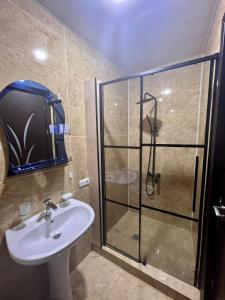 La salle de bains est pourvue d'un lavabo et d'une douche en verre. dans l'établissement Luxure Apartments, à Batoumi