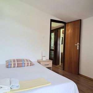a bedroom with a white bed and a wooden door at Guest House Tanja in Babino Polje