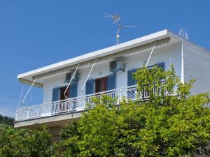 ein weißes Gebäude mit einem Balkon und Bäumen in der Unterkunft Magdas house in Alonnisos Altstadt