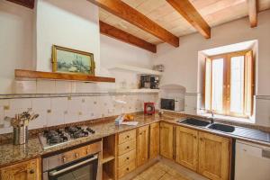 kuchnia z drewnianymi szafkami, umywalką i oknem w obiekcie Can Mascaro w Manacorze