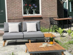 a couch on a patio with a table and a bottle of wine at Vacation home in Schoonloo with terrace in Schoonloo