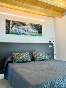 1 dormitorio con 1 cama con una pintura en la pared en Residenza Orchidee, en Costermano