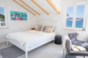 a white bedroom with a bed and a chair at Seafront Baska Apartment in Baška