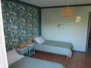 1 dormitorio con 2 camas y pared con papel pintado en Les Milahinas en Lescure-dʼAlbigeois