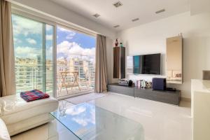 a living room with a tv and a large window at Exquisite Seafront Apart in Spinola Bay St Julians in Paceville