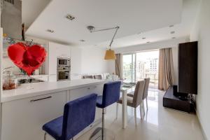 a kitchen with a table with blue chairs and a heart balloon at Exquisite Seafront Apart in Spinola Bay St Julians in Paceville