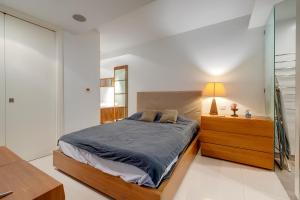 ein Schlafzimmer mit einem Bett und einem Nachttisch mit einer Lampe in der Unterkunft Exquisite Seafront Apart in Spinola Bay St Julians in Paceville