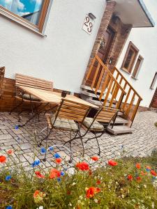a wooden bench sitting outside of a house with flowers at Ferienwohnung “Mount Meißner” in Germerode