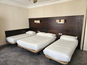 grupa trzech łóżek w pokoju w obiekcie Hôtel Bellevue et du Chariot d'Or w Paryżu