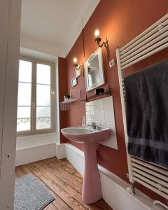 ein Bad mit einem rosa Waschbecken und einem Fenster in der Unterkunft Chez La Vieille Dame in Cosne Cours sur Loire