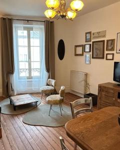 ein Wohnzimmer mit Stühlen, einem Tisch und einem TV in der Unterkunft Chez La Vieille Dame in Cosne Cours sur Loire