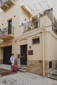 dos mujeres de pie fuera de un edificio con equipaje en La Bifora e il granaio, en Sciacca