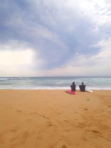 zwei Leute sitzen am Strand und blicken auf den Ozean in der Unterkunft Superbe studio à 8mn en voiture de la plage in Linxe