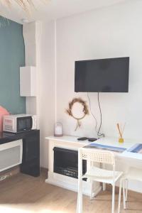 Dieses weiße Zimmer verfügt über einen Schreibtisch mit einem TV an der Wand. in der Unterkunft Superbe studio à 8mn en voiture de la plage in Linxe