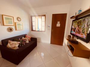 a living room with a couch and a flat screen tv at Casas Aconchegantes Temporada in Cabo Frio