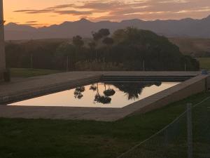 a swimming pool with a sunset in the background at Brancott Ridge in Renwick