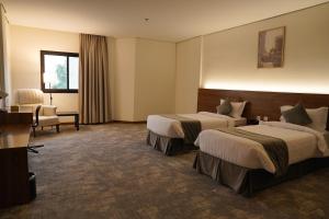 a hotel room with two beds and a chair at Kara Hotel فندق كارا in Al Khobar