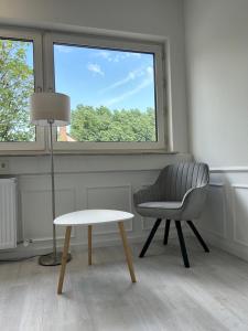 una silla y una mesa en una habitación con ventana en MyCompass Hotel Offenbach en Offenbach