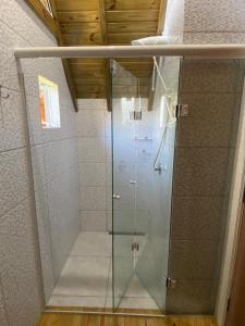 a shower with a glass door in a bathroom at Chalés Snow in Urubici