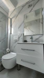 a white bathroom with a toilet and a mirror at Jiovanni in Parga