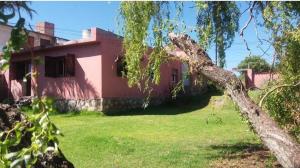 a house with a tree in front of a yard at Casa con vista a la salida del sol in La Cumbre