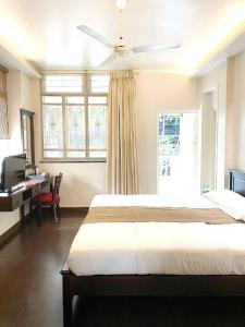 a bedroom with a large bed with a ceiling fan at Hotel Ketan in Pune