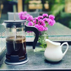 Hotel Ketan في بيون: وعاء قهوة و إناء من الزهور على طاولة