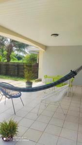 a porch with a hammock and chairs on a patio at Maison du Lac - jusqu'à 4 personnes in Rémire-Camp