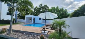 a villa with a pool and an umbrella at Serenity Haven - Your Ultimate Runaway Bay Escape in Runaway Bay